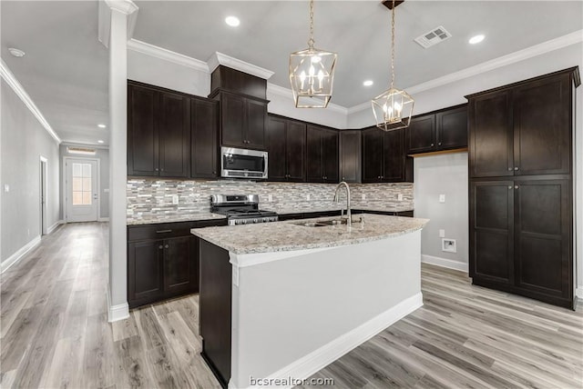 kitchen featuring appliances with stainless steel finishes, light wood-type flooring, a kitchen island with sink, and ornamental molding