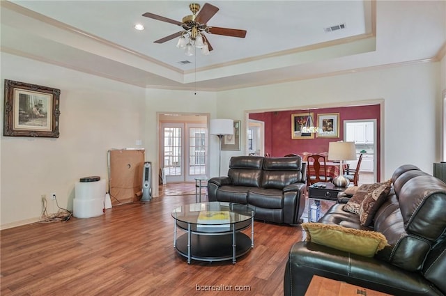 living room with a tray ceiling, ceiling fan, ornamental molding, and hardwood / wood-style flooring