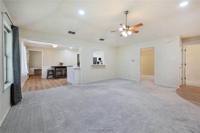 unfurnished living room featuring ceiling fan and light carpet