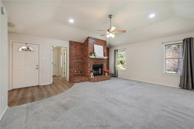 unfurnished living room with a brick fireplace, plenty of natural light, ceiling fan, and vaulted ceiling