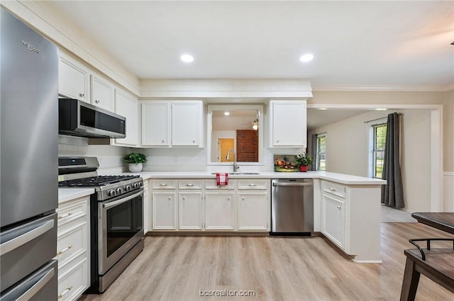 kitchen featuring kitchen peninsula, stainless steel appliances, sink, light hardwood / wood-style flooring, and white cabinetry