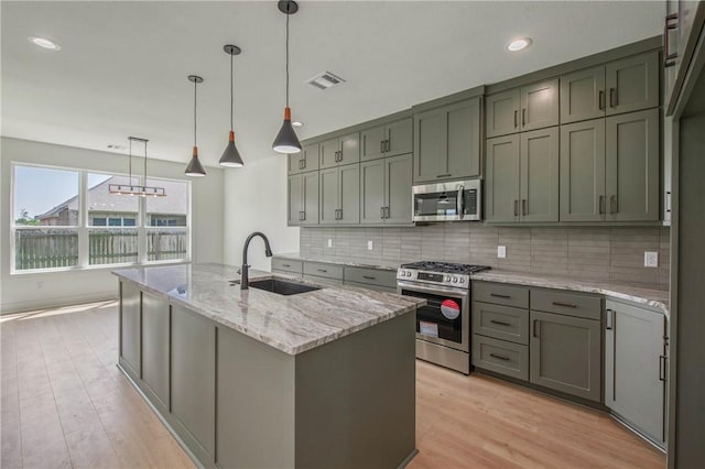 3034 Teller Dr, Bryan, TX 77808 - kitchen featuring a sink, appliances with stainless steel finishes, decorative backsplash, light stone countertops, and light wood-style flooring
