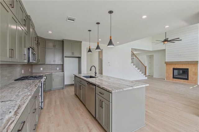 3034 Teller Dr, Bryan, TX 77808 - kitchen featuring appliances with stainless steel finishes, a sink, gray cabinets, light wood finished floors, and backsplash