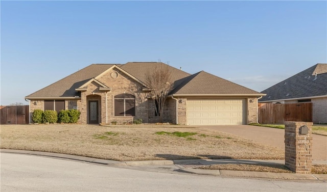 ranch-style house with a shingled roof, concrete driveway, an attached garage, fence, and brick siding