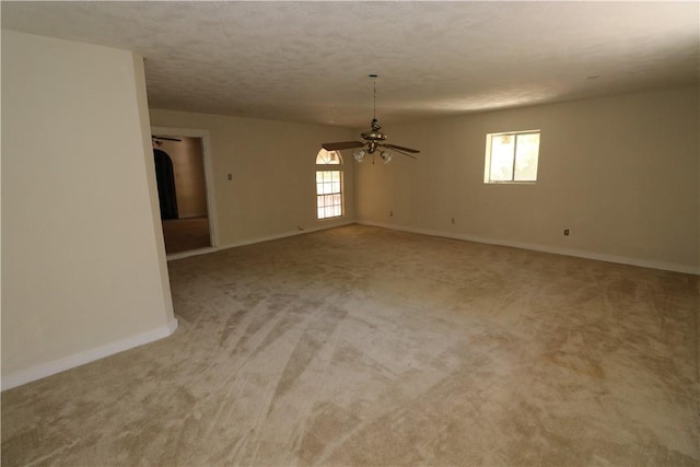 spare room featuring a wealth of natural light, ceiling fan, light carpet, and a textured ceiling