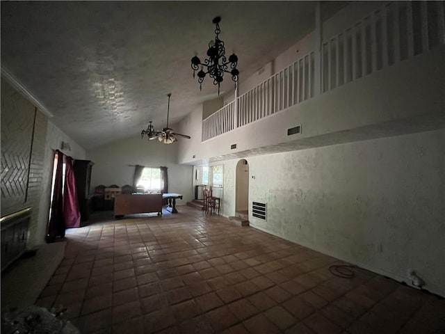 unfurnished living room with tile patterned flooring, ceiling fan with notable chandelier, and high vaulted ceiling