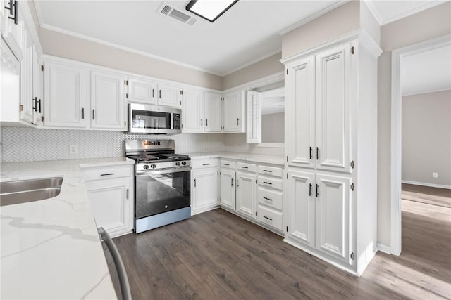 kitchen featuring white cabinets, appliances with stainless steel finishes, decorative backsplash, dark hardwood / wood-style floors, and light stone counters