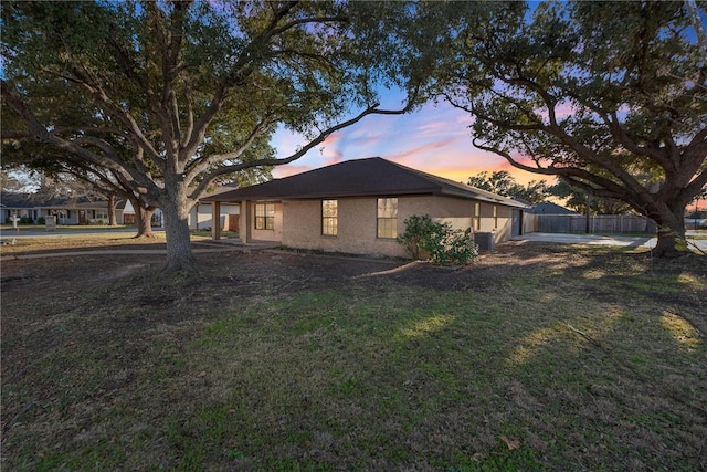 property exterior at dusk with central AC unit and a yard