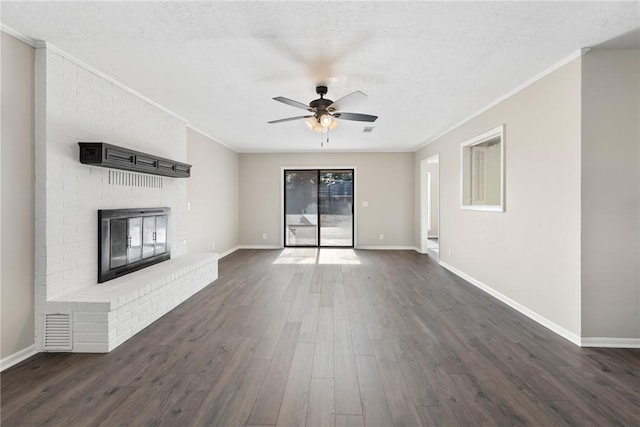 unfurnished living room with ceiling fan, dark hardwood / wood-style floors, a fireplace, a textured ceiling, and ornamental molding