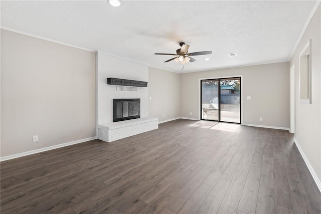 unfurnished living room featuring ceiling fan, dark wood-type flooring, ornamental molding, and a fireplace