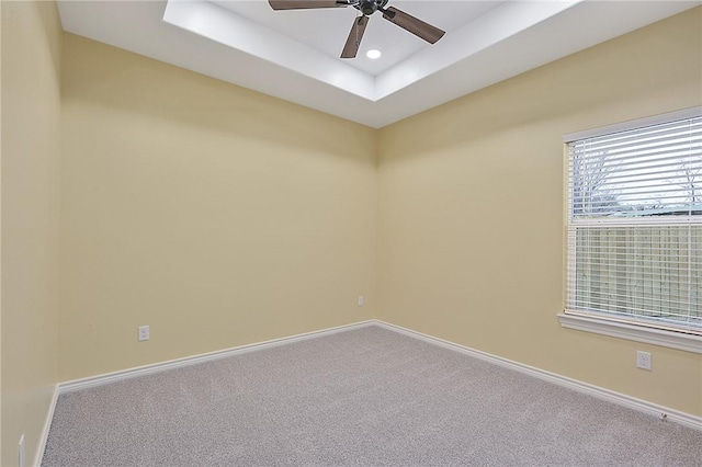 unfurnished room featuring ceiling fan, a tray ceiling, and carpet