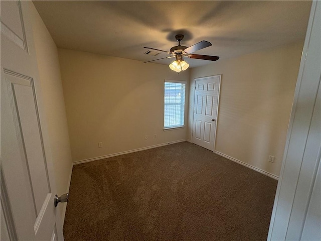 unfurnished room with dark carpet and ceiling fan