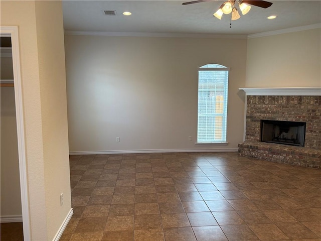 unfurnished living room featuring ceiling fan, crown molding, dark tile patterned floors, and a brick fireplace