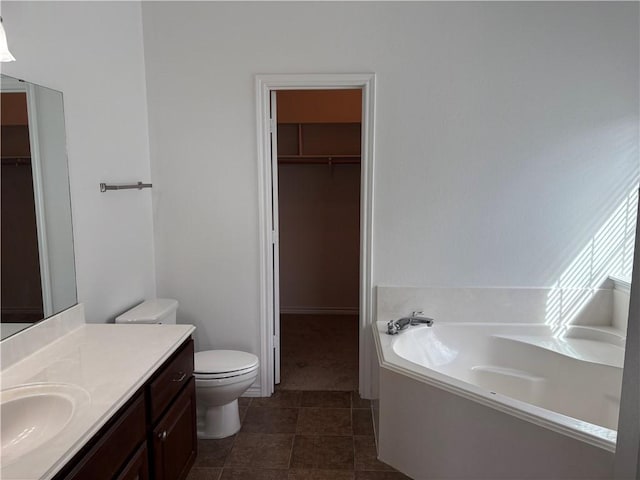 bathroom with toilet, vanity, a tub to relax in, and tile patterned floors