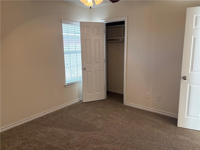 unfurnished bedroom featuring dark colored carpet, ceiling fan, and a closet