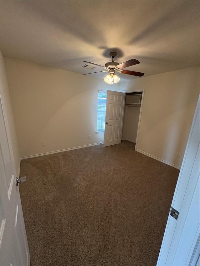 unfurnished bedroom with dark colored carpet, ceiling fan, and a closet