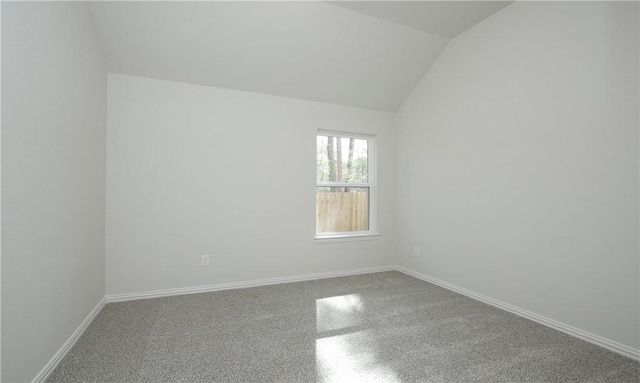 empty room with carpet floors and vaulted ceiling