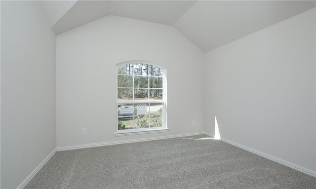 carpeted spare room featuring vaulted ceiling