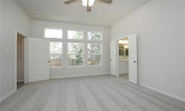 unfurnished bedroom with ceiling fan, ensuite bath, and light carpet