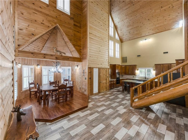 206 22 Hills Rd, Gause, TX 77857 - dining room featuring high vaulted ceiling, wooden walls, a chandelier, and stairway