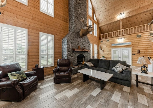 206 22 Hills Rd, Gause, TX 77857 - living area featuring high vaulted ceiling, wood-type flooring, a stone fireplace, log walls, and french doors