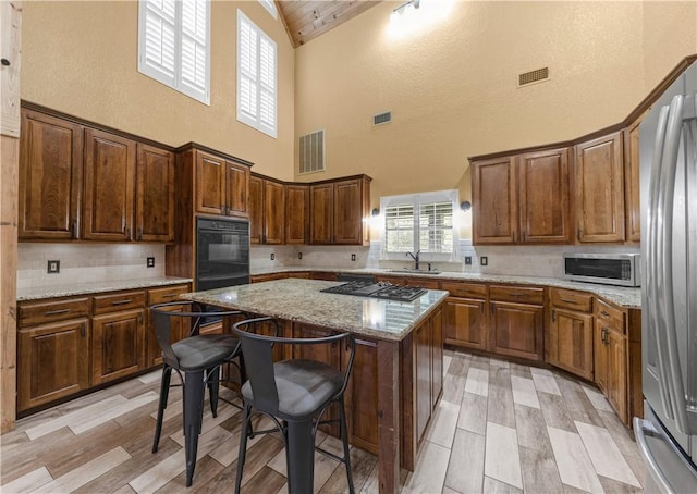 206 22 Hills Rd, Gause, TX 77857 - kitchen featuring stainless steel appliances, high vaulted ceiling, tasteful backsplash, a kitchen island, and a kitchen breakfast bar