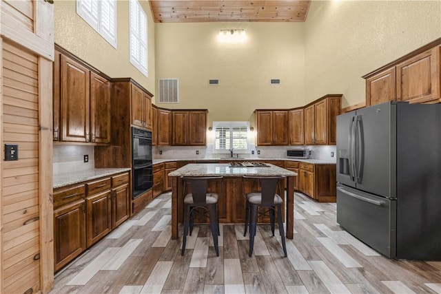 206 22 Hills Rd, Gause, TX 77857 - kitchen with appliances with stainless steel finishes, a towering ceiling, a kitchen island, wooden ceiling, and a breakfast bar area