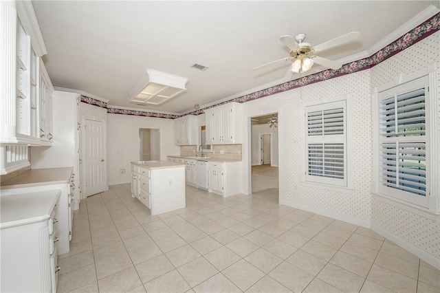 kitchen featuring dishwasher, white cabinetry, a kitchen island, and crown molding