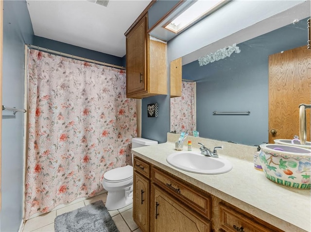 bathroom with tile patterned flooring, a skylight, vanity, and toilet