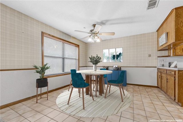 dining space with light tile patterned floors, visible vents, baseboards, and wallpapered walls