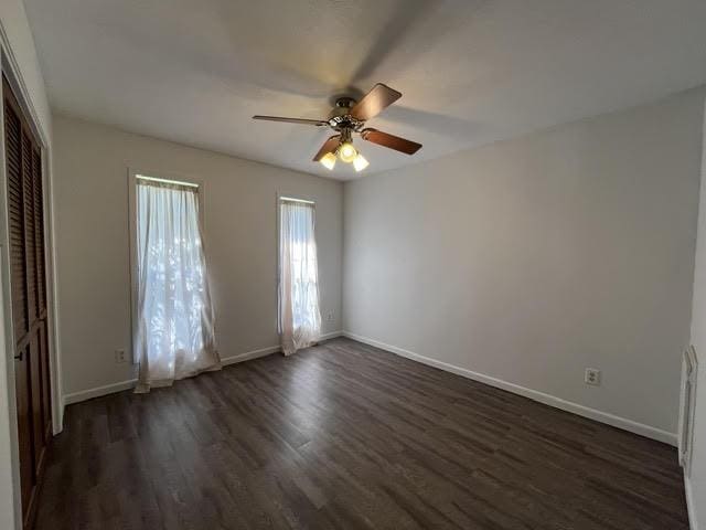 spare room with ceiling fan, baseboards, and dark wood-type flooring