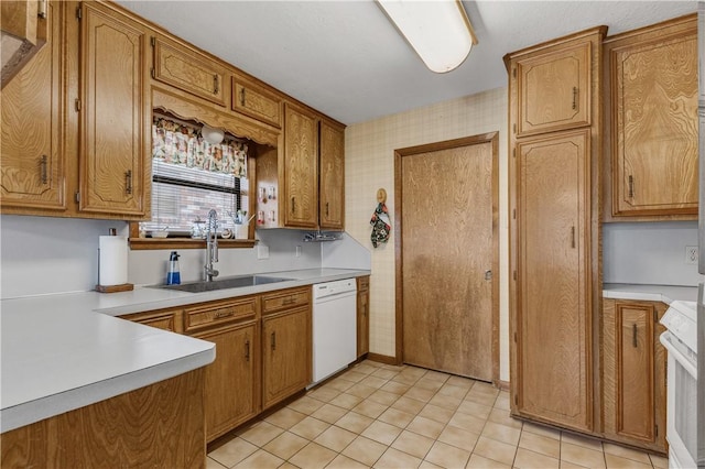 kitchen with brown cabinets, light countertops, a sink, dishwasher, and wallpapered walls