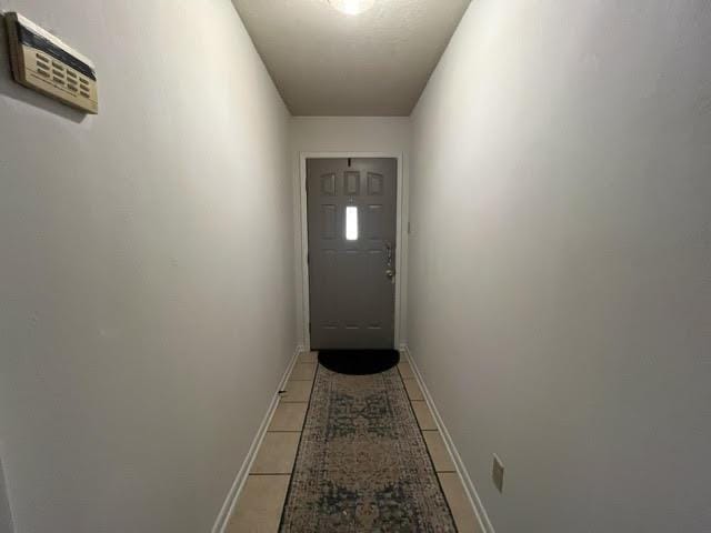 doorway featuring light tile patterned flooring and baseboards