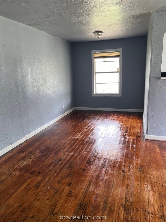 unfurnished room with a textured ceiling and dark hardwood / wood-style flooring