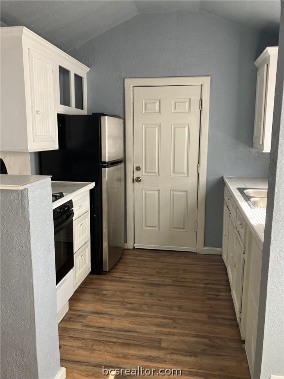 kitchen featuring stainless steel refrigerator, white cabinetry, dark wood-type flooring, vaulted ceiling, and black oven