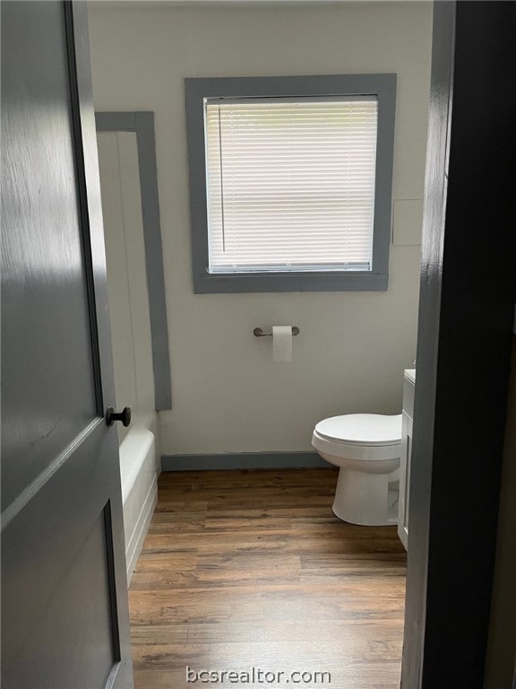 bathroom featuring vanity, toilet, wood-type flooring, and a washtub