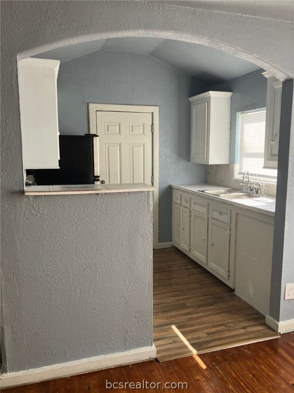 kitchen featuring vaulted ceiling, dark wood-type flooring, sink, white cabinetry, and fridge