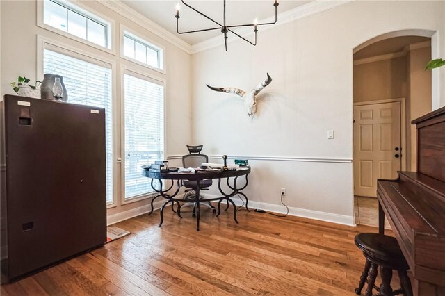 dining space with wood finished floors, baseboards, arched walkways, and ornamental molding