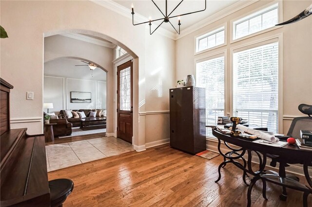 home office featuring baseboards, light wood-style flooring, arched walkways, ornamental molding, and a chandelier