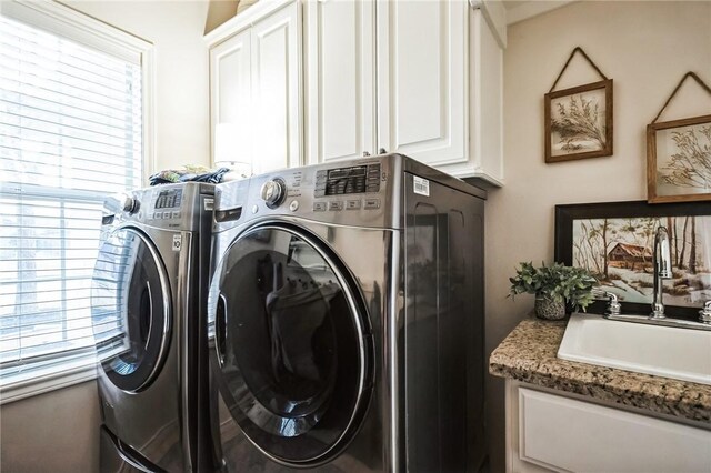 laundry area featuring washing machine and dryer, cabinet space, and a sink