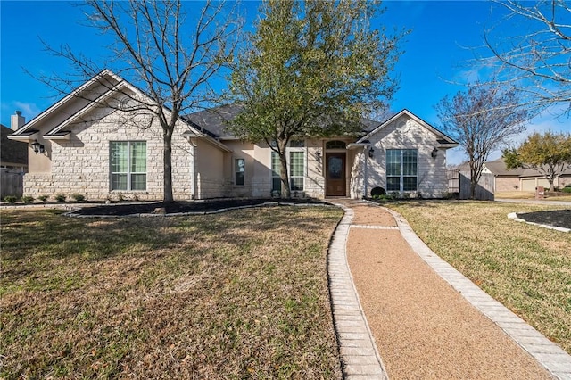 view of front of house featuring stone siding, a front yard, and fence