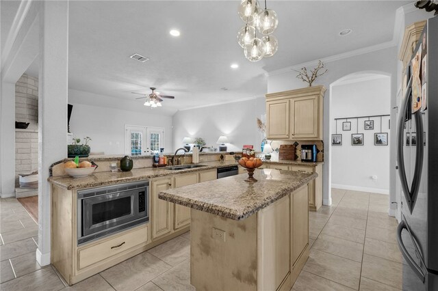 kitchen with a kitchen island, light brown cabinetry, appliances with stainless steel finishes, a peninsula, and a sink