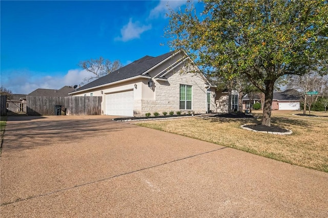 view of front facade featuring fence, driveway, a front lawn, a garage, and stone siding