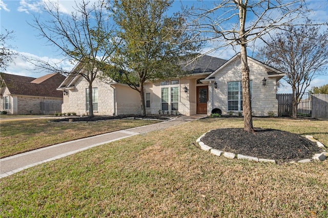 ranch-style home featuring a front lawn, fence, and stone siding