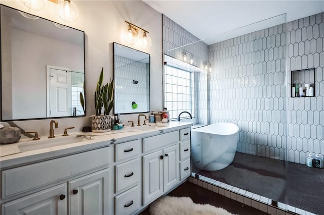 bathroom featuring a sink, a freestanding bath, tile walls, and double vanity