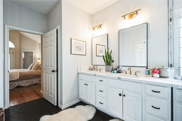 bathroom featuring a sink, connected bathroom, baseboards, and double vanity