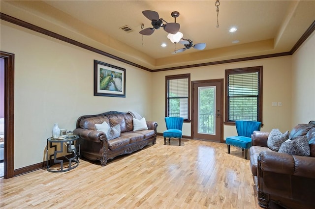 living area with baseboards, a raised ceiling, visible vents, and wood finished floors