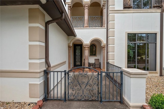 doorway to property featuring a gate, stucco siding, and covered porch