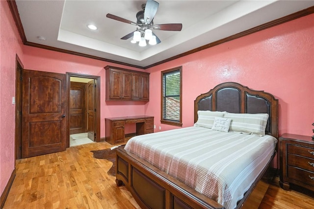 bedroom with ornamental molding, recessed lighting, ceiling fan, light wood-style flooring, and a tray ceiling