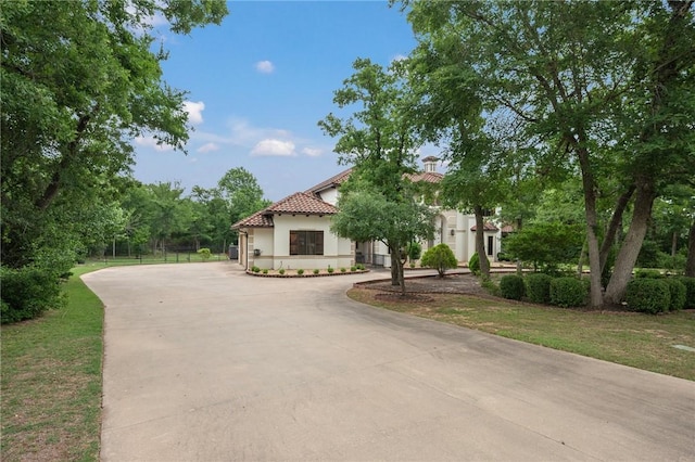 mediterranean / spanish house featuring curved driveway, a tile roof, and stucco siding